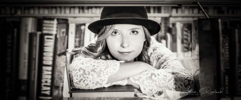 girl with books all around her senior portrait in santa cruz