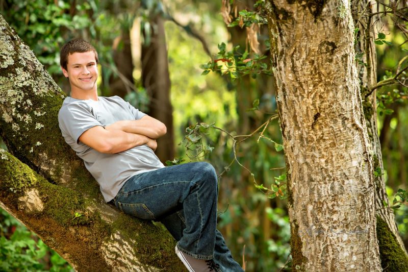 High school senior portrait Of boy in tree